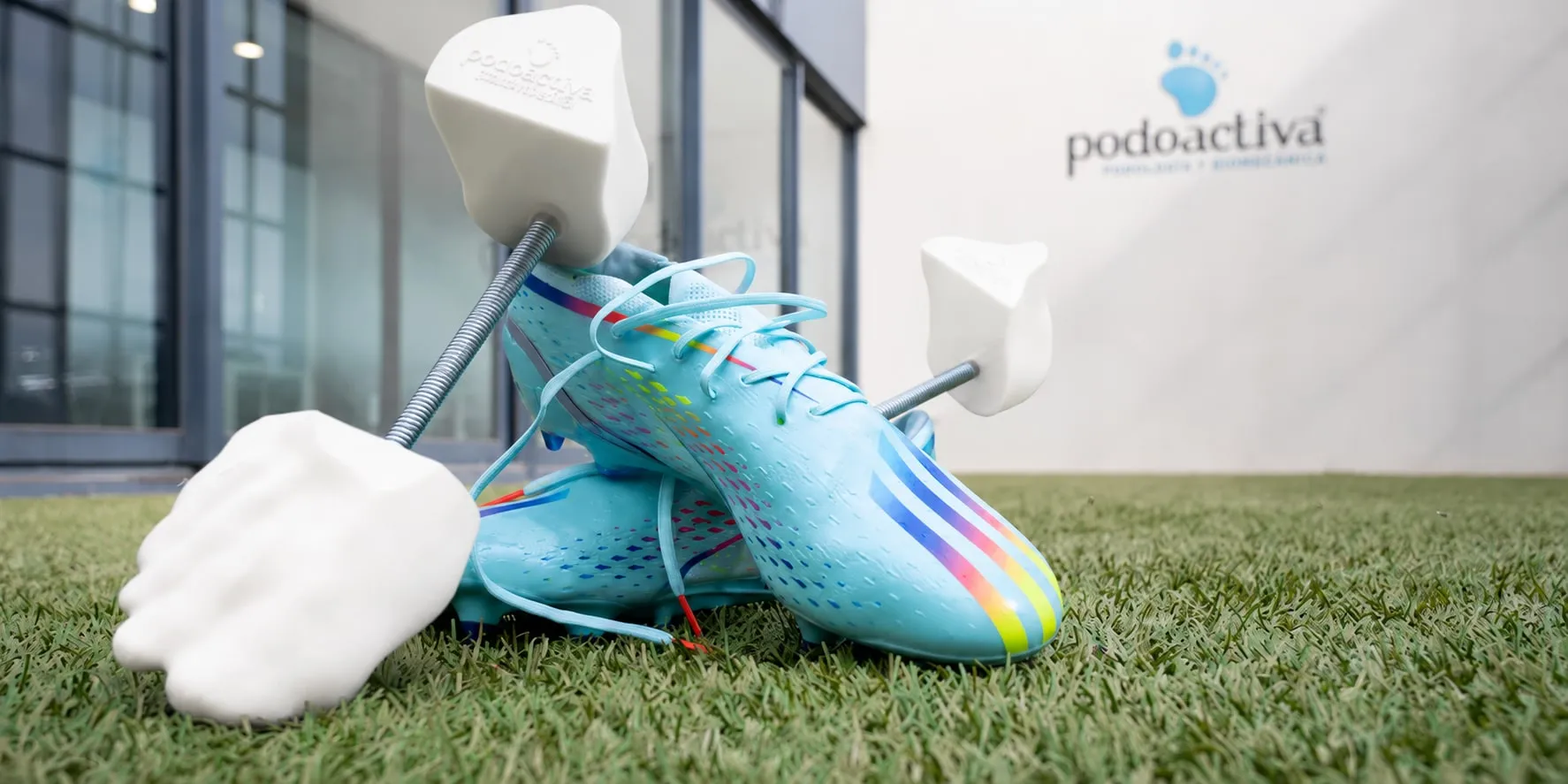 Hormas personalizadas impresas en 3D junto a una bota de fútbol sobre césped