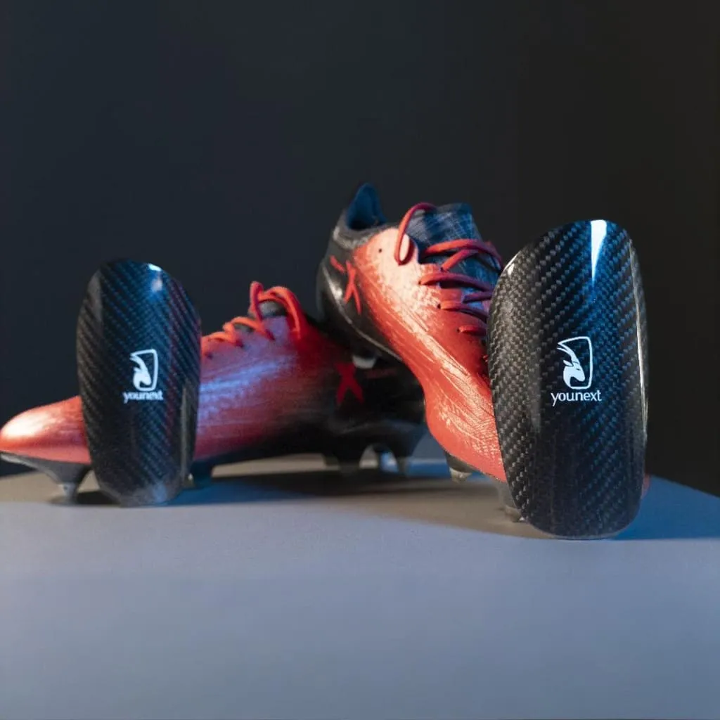 Carbon Protection carbon fibre shin guards next to football boots